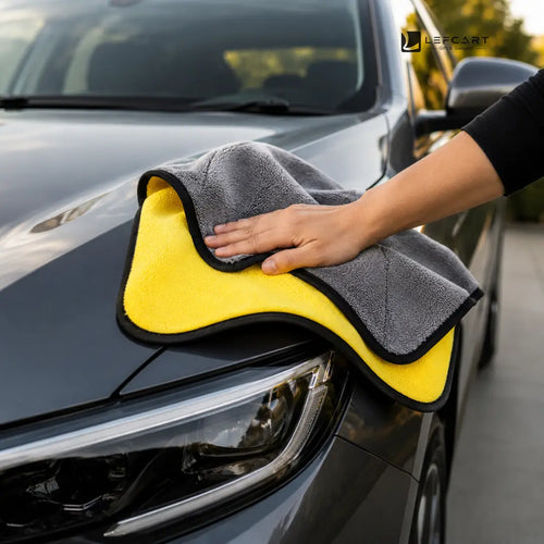 A close-up of a person's hand wiping a dark gray car hood with a yellow and gray microfiber cloth featuring a black border. The Leechart brand logo is visible in the top right corner.
